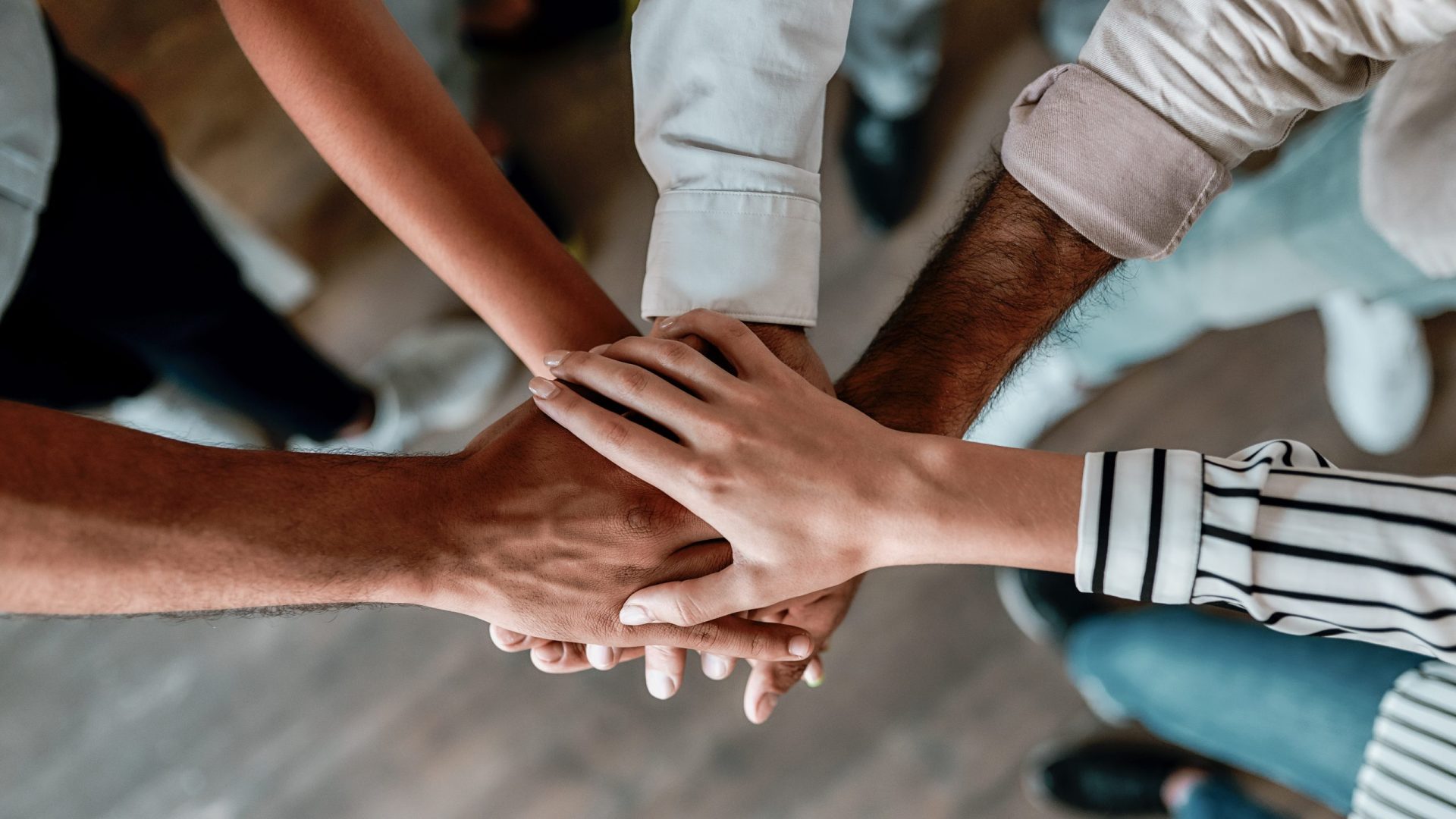 Cooperation. Top view of people holding hands together while standing in the office A group of people putting their hands together in support