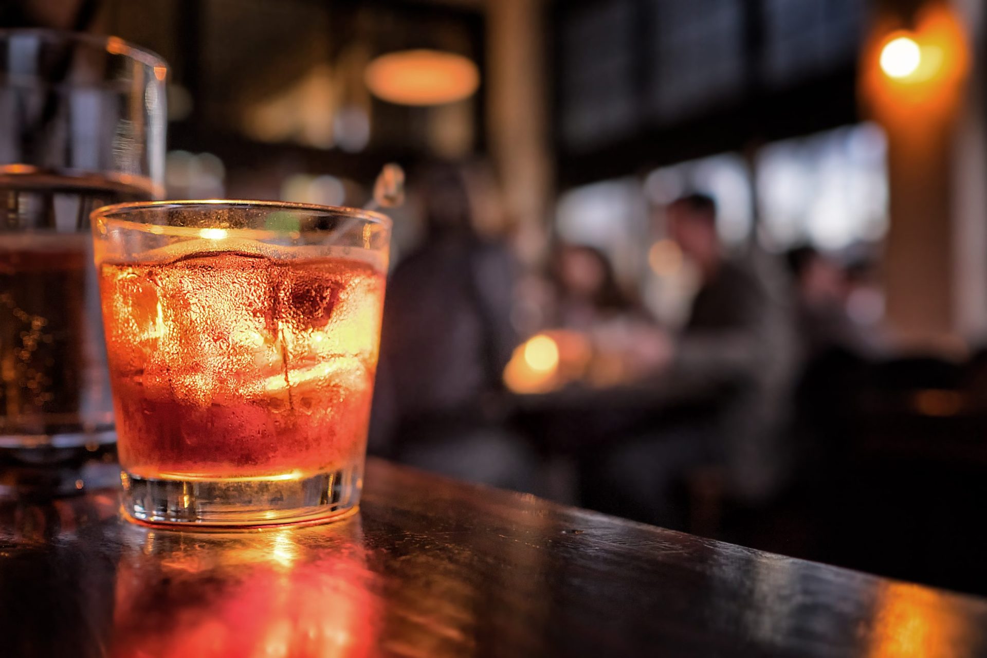 Cocktail close up in a bar setting. Blurred people in the background. Selective focus on the icy drink and glass.