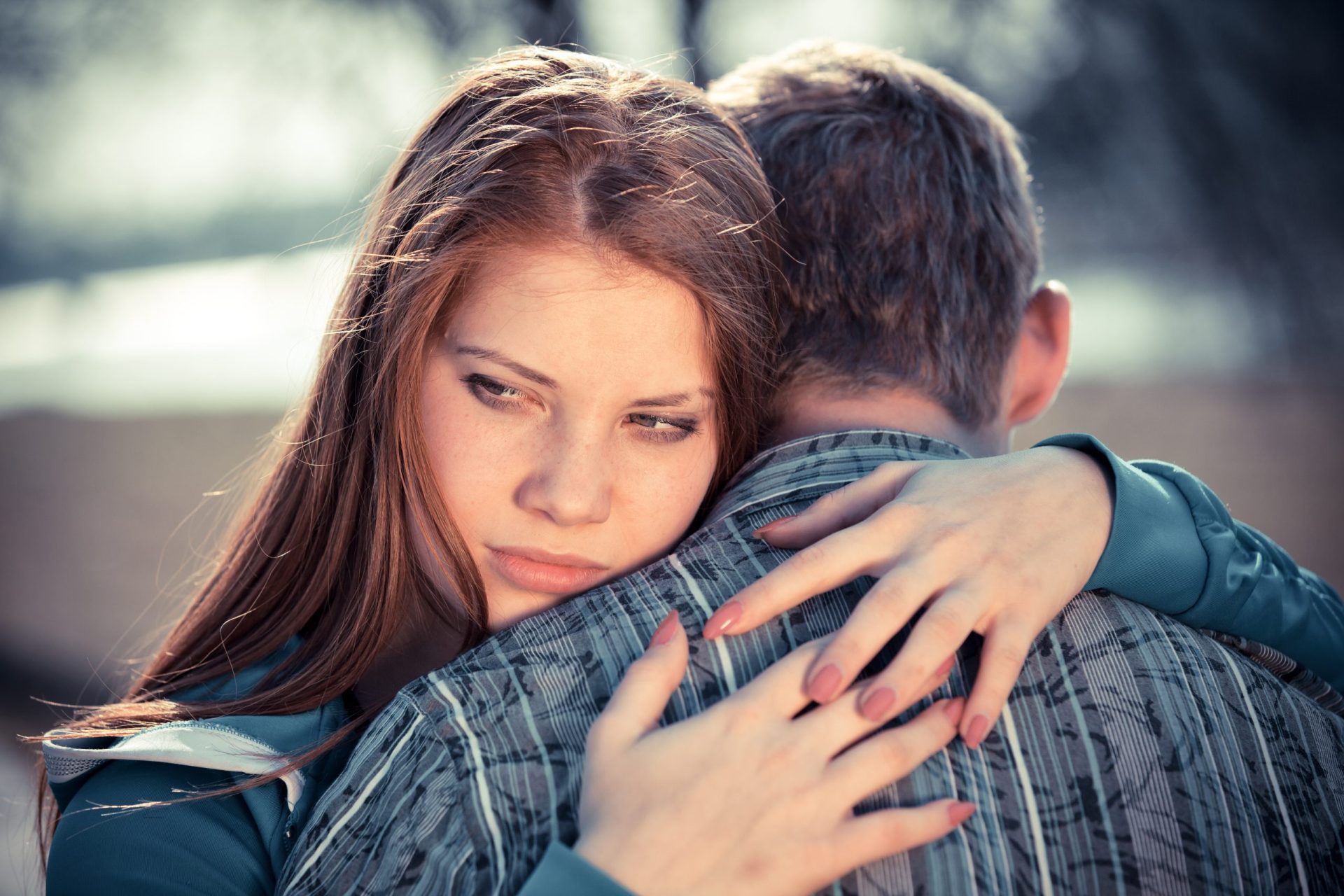 Couple hugging, teen girl looking unhappy