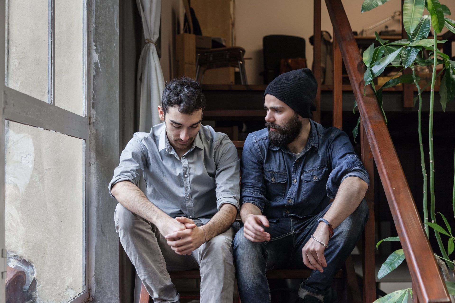 Couple of young men talking on the stairs of an office Two men sitting on stairs talking