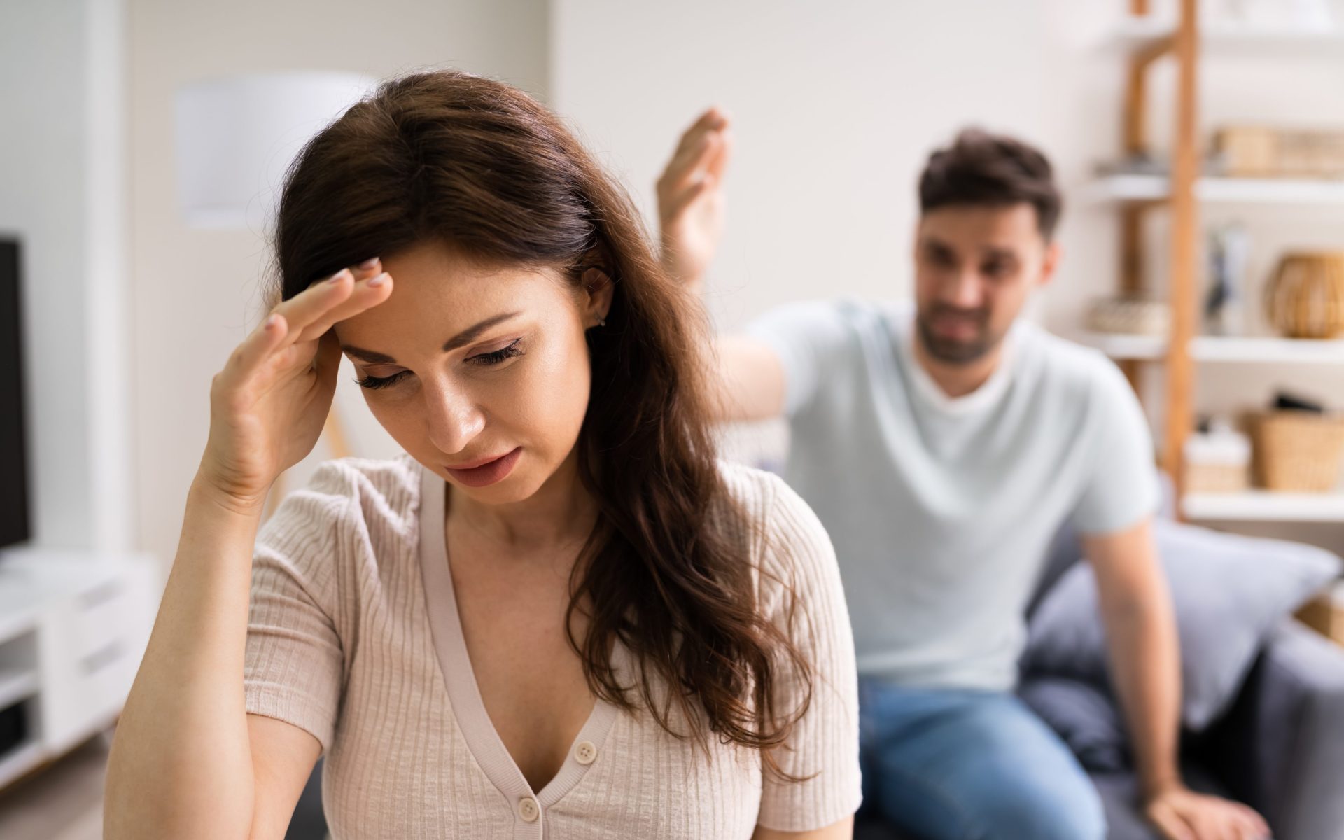 abuse Couple appearing to be in a fight, woman in foreground with hand to her head