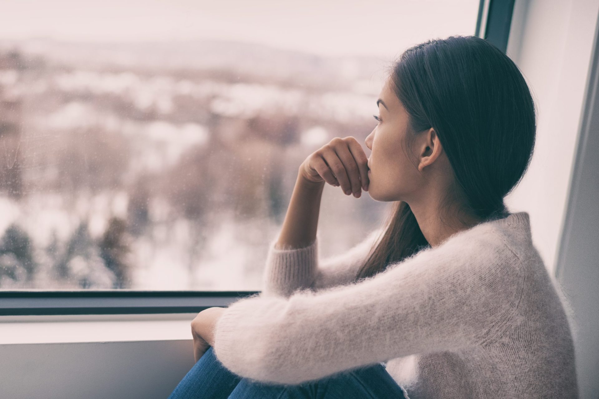 Woman looking out winter at dreary weather