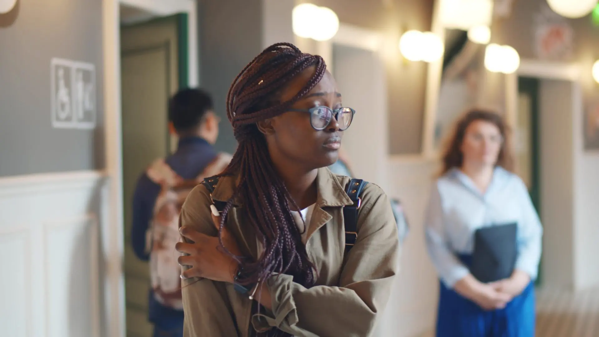 Depressed afro-american female student walking in college corridor