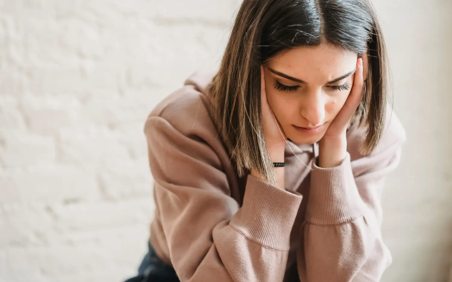 woman sitting with her head in her hands looking sad