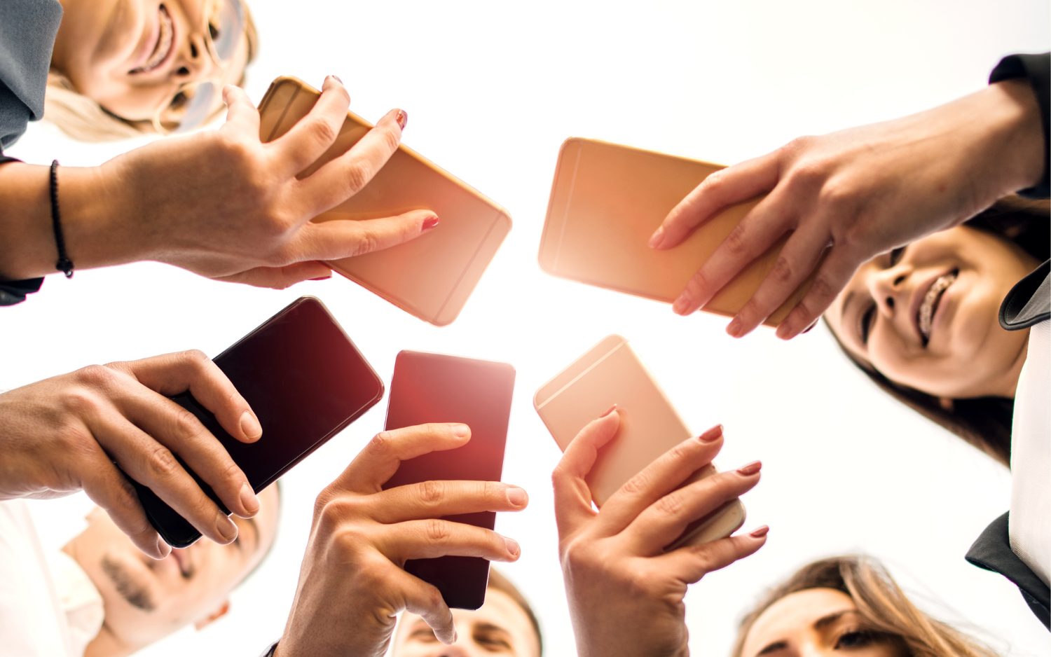 Group of people standing together all looking at their phones with varying facial expressions