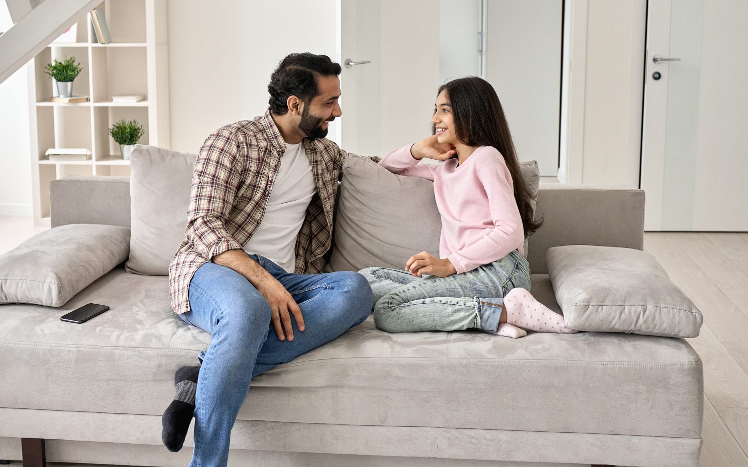 Father sitting on couch talking with teenage daughter