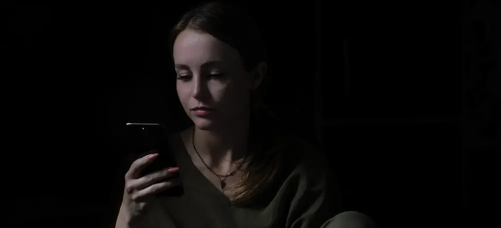 Teenage girl holding her phone to contact crisis hotlines.