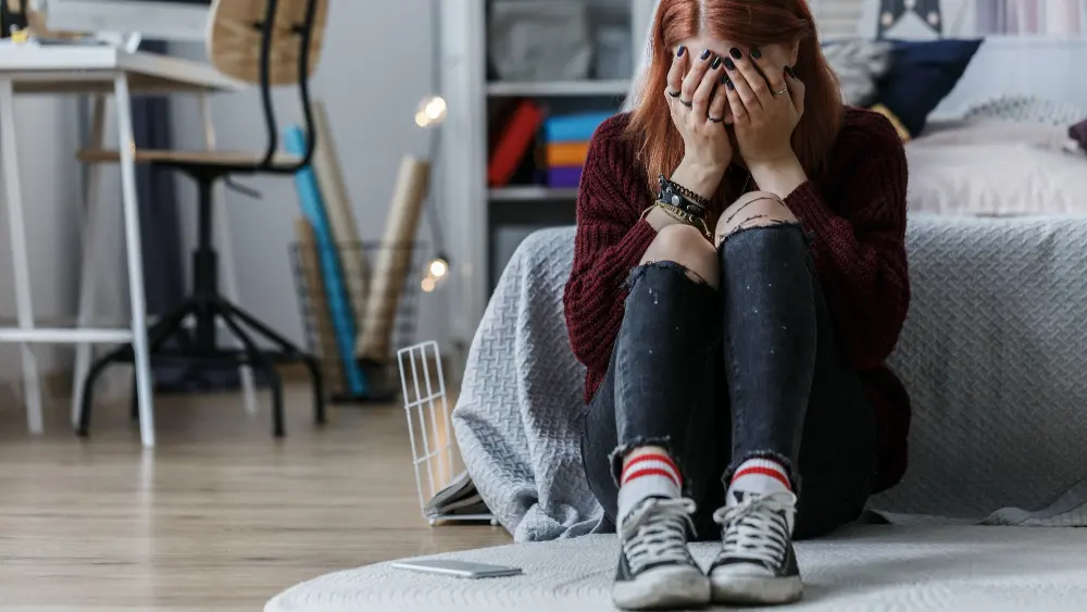 Teenage girl sitting on the floor and crying