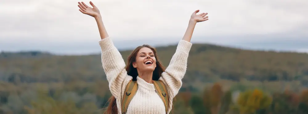 Young woman with her hands in the air, hopeful.