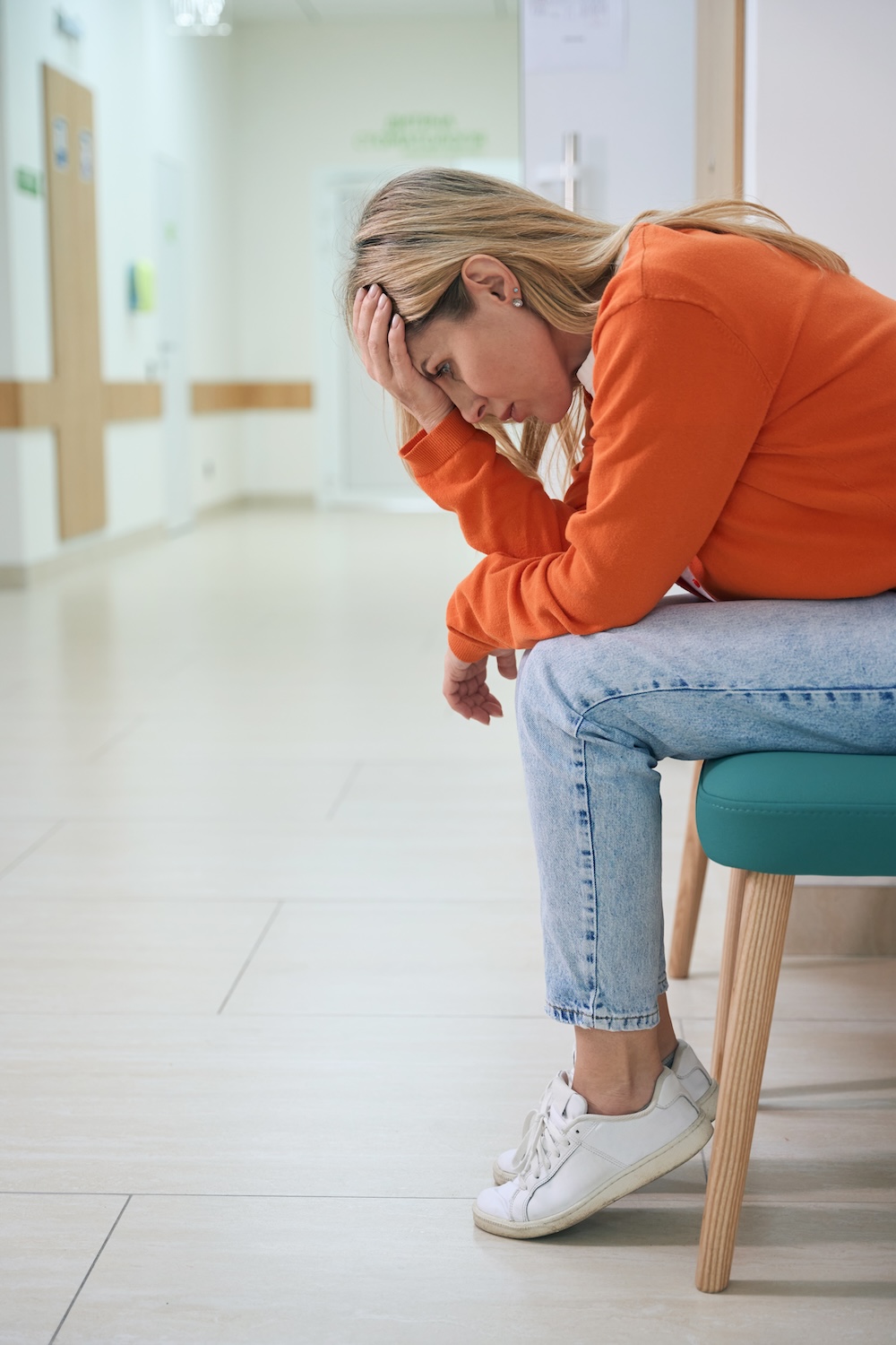 Blonde female sitting outside doctors office.