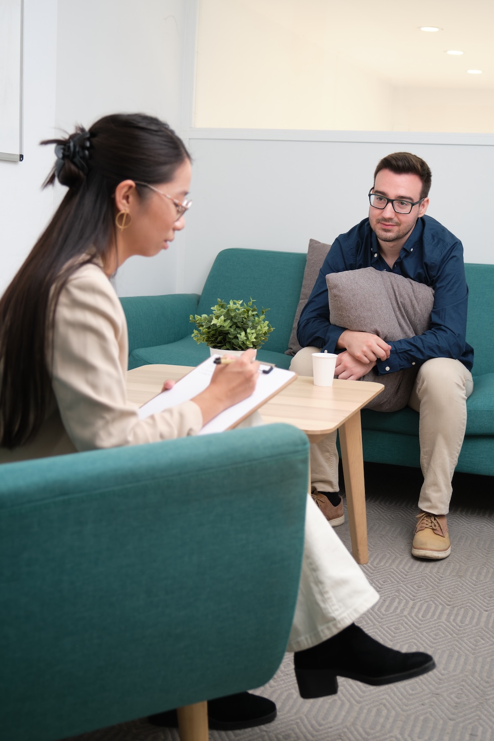 Professional psychologist carefully making notes during a treatment interview. 