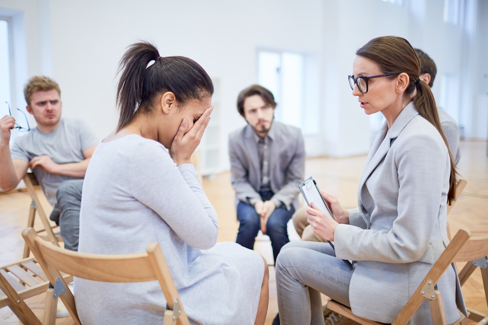 Clinician consoling upset client in group therapy session