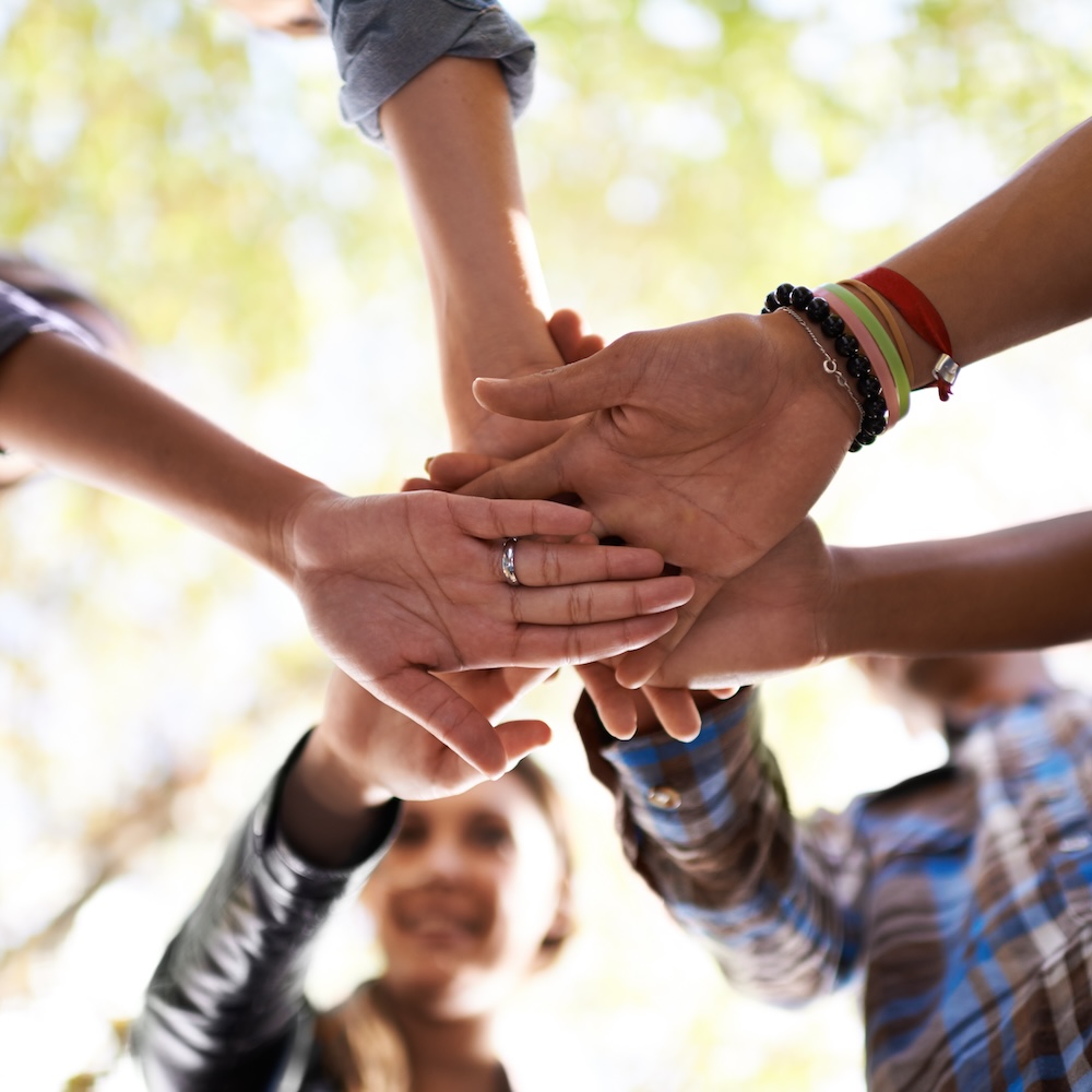 A group of friends standing in a huddle with their hands piled